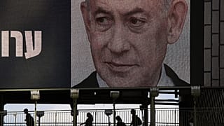 أشخاص يعبرون جسراً أسفل إعلان انتخابي متلفز لرئيس الوزراء الإسرائيلي بنيامين نتنياهو في رمات غان، قبيل الانتخابات العامة، الأحد 18 أكتوبر 2026.