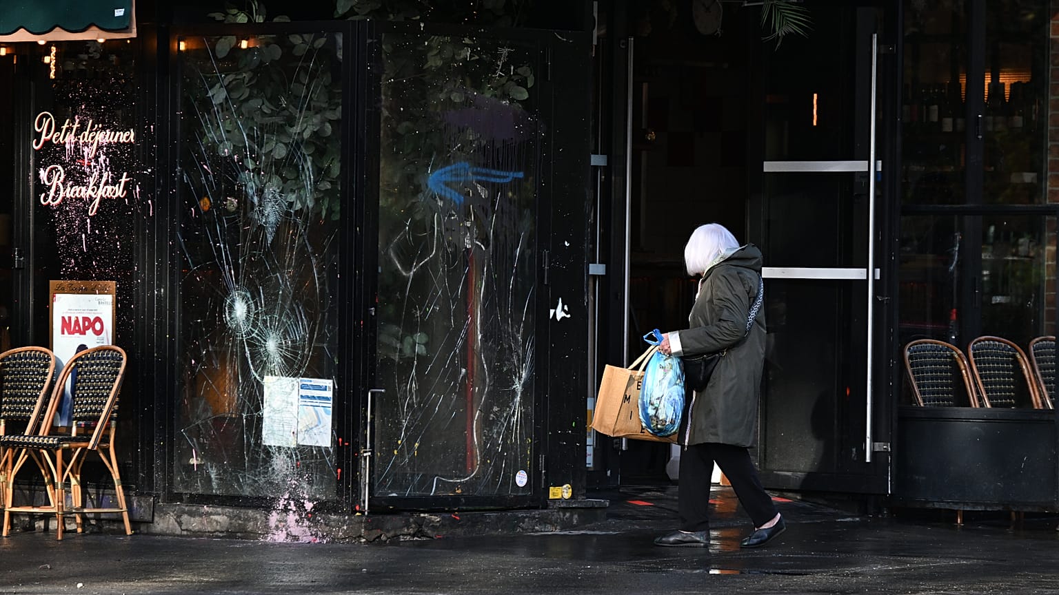 A woman walks past a vandalized bar the day after a demonstration against rising living costs, joining students' grievances, in Paris, Sunday, Oct. 18, 2026.