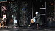 A woman walks past a vandalized bar the day after a demonstration against rising living costs, joining students' grievances, in Paris, Sunday, Oct. 18, 2026.