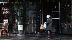 Una mujer pasa junto a un bar vandalizado tras una protesta contra el aumento del coste de la vida y las reivindicaciones estudiantiles en París, el 18 de octubre de 2026
