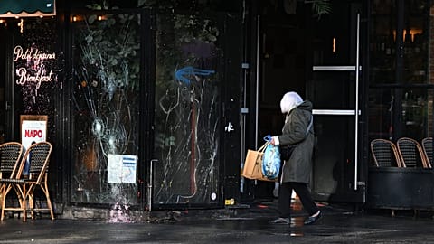 A woman walks past a vandalized bar the day after a demonstration against rising living costs, joining students' grievances, in Paris, Sunday, Oct. 18, 2026.