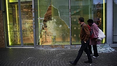 Paris’te 19 Ekim’de, artan yaşam maliyeti ve okullardaki kötü koşullara karşı protestoların şiddete dönüşmesinin ardından insanlar yağmalanan mağazanın önünden geçiyor.