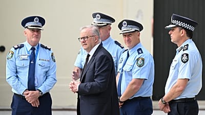 ARCHIV: Australiens Premierminister Anthony Albanese (Mitte) lässt sich nach dem Niederlegen von Blumen am Bondi Pavilion einen Tag nach der Schießerei beraten.