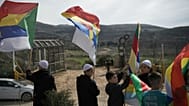 أفراد من الطائفة الدرزية ورجال الدين ينتظرون قرب الحدود الحافلات التي تقل أفراداً من الطائفة الدرزية السورية للعبور من سوريا في قرية مجدل شمس في مرتفعات الجولان