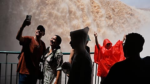 Tourists stand on a walkway overlooking Iguazu Falls in Foz do Iguacu, Brazil, Oct. 16, 2026. Days earlier, the falls were temporarily closed to visitors due to flood fears.