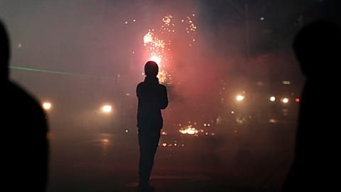 Un manifestante lanza fuegos artificiales contra la policía antidisturbios durante una protesta antigubernamental en Tirana, Albania