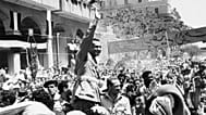 جمال عبد الناصر يلوّح خلال احتفال بتسلّم مصر رسميًا السيطرة على قناة السويس من بريطانيا في بورسعيد، 18 حزيران/يونيو 1956. 