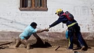 ARCHIVO: Un rescatista extiende su mano para ayudar a un lugareño a cruzar una calle cubierta de lodo en Chanaral, Chile, en marzo de 2015.