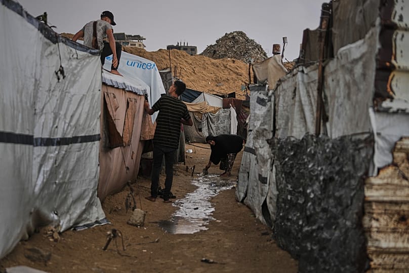 فلسطينيون نازحون يصلحون خيمتهم بعد هطول الأمطار في مدينة غزة، الأحد 18 أكتوبر 2026.
