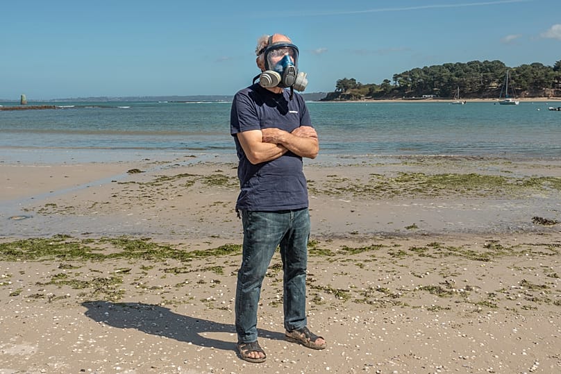 L'écologiste Yves-Marie Le Lay montre le masque qu'il porte lorsque les algues atteignent des niveaux dangereux sur la plage du Fond de la Baie, à Locquirec, en Bretagne.