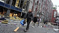  carry their belongings as they leave their office following a Russian air attack in Kyiv