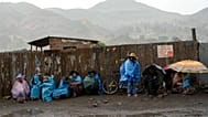 ARCHIVO: Residentes se resguardan de la lluvia en un bloqueo de carretera instalado en Sicuani, Perú, el 28 de enero de 2023.