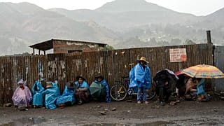 ARCHIVO: Residentes se resguardan de la lluvia en un bloqueo de carretera instalado en Sicuani, Perú, el 28 de enero de 2023.