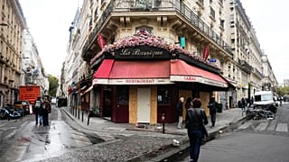 Des passants déambulent devant le bistrot La Barrique, endommagé après les émeutes et les pillages qui ont suivi les manifestations du 17 octobre à Paris.