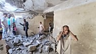 Moradores caminham entre os destroços das suas casas no bairro Seina, em Taiz, no Iémen, após um ataque com mísseis