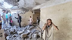 Residents walk on debris of their homes at Seina district in Taiz, Yemen, after a missile strike