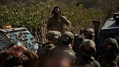 مستوطن إسرائيلي يراقب قوات إسرائيلية تمنع الفلسطينيين من الوصول إلى حقول الزيتون لقطف محصولهم في بلدة ترمسعيا بالضفة الغربية، 21 تشرين الأول/أكتوبر 2026