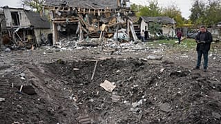 Egy férfi egy krátert néz egy orosz rakétacsapás után Kijevben.