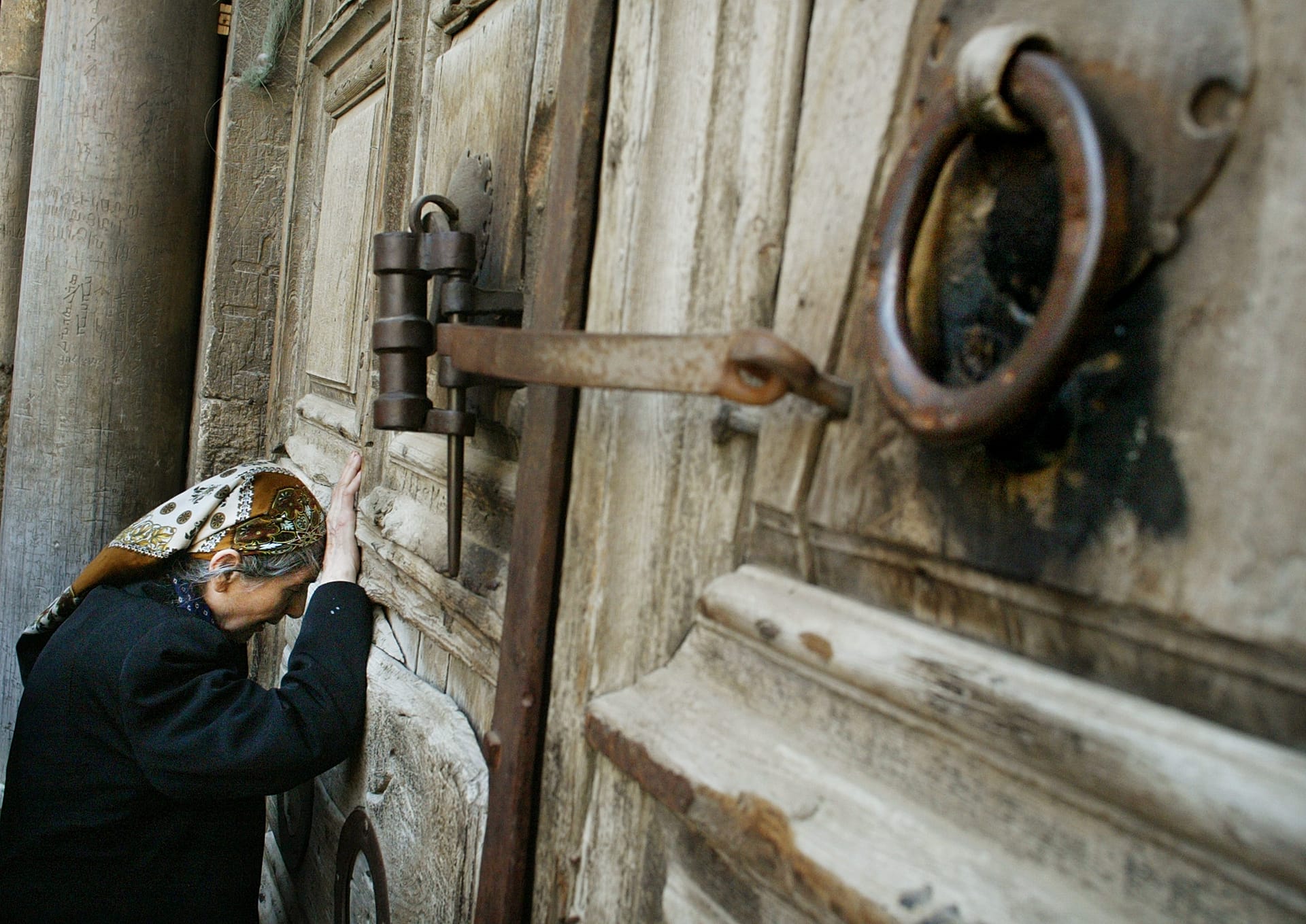 A Christian pilgrim prays in front of the doors of the Church of the Holy Sepulchre in Jerusalem's Old City.