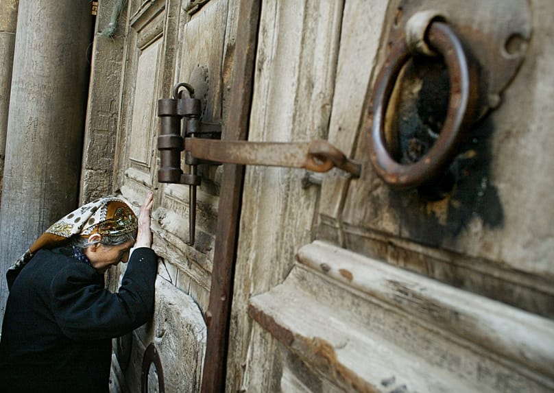 Eine christliche Pilgerin betet vor den Türen der Grabeskirche in der Jerusalemer Altstadt.