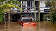 FILE- A man sits on the balcony of a house surrounded by floodwaters in Port Macquarie, north of Sydney, Australia, Friday, May 23, 2025. (Lindsay Moller/AAP Image via AP)