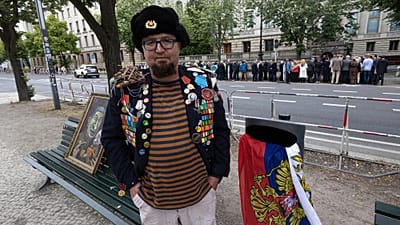 Siemion Skrepecki lässt sich am zwölf. Juni 2026 nahe der Russischen Botschaft in Berlin in Deutschland mit einem seiner Bilder fotografieren.