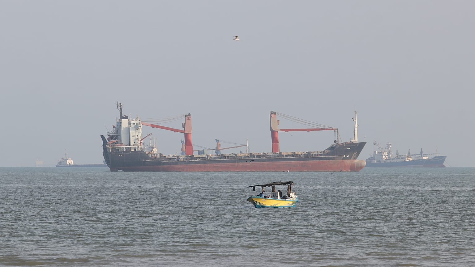 FILE: A boat floats as commercial vessels appear anchored in the Strait of Hormuz off Bandar Abbas, 13 October 2026
