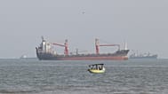 FILE: A boat floats as commercial vessels appear anchored in the Strait of Hormuz off Bandar Abbas, 13 October 2026