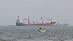 FILE: A boat floats as commercial vessels appear anchored in the Strait of Hormuz off Bandar Abbas, 13 October 2026