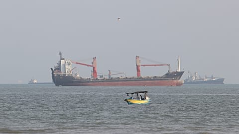 FILE: A boat floats as commercial vessels appear anchored in the Strait of Hormuz off Bandar Abbas, 13 October 2026