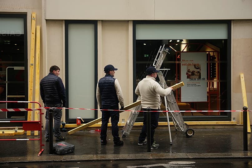 Arbeiter vernageln ein Schaufenster am Vorabend weiterer Proteste in Paris, 23. Oktober 2026