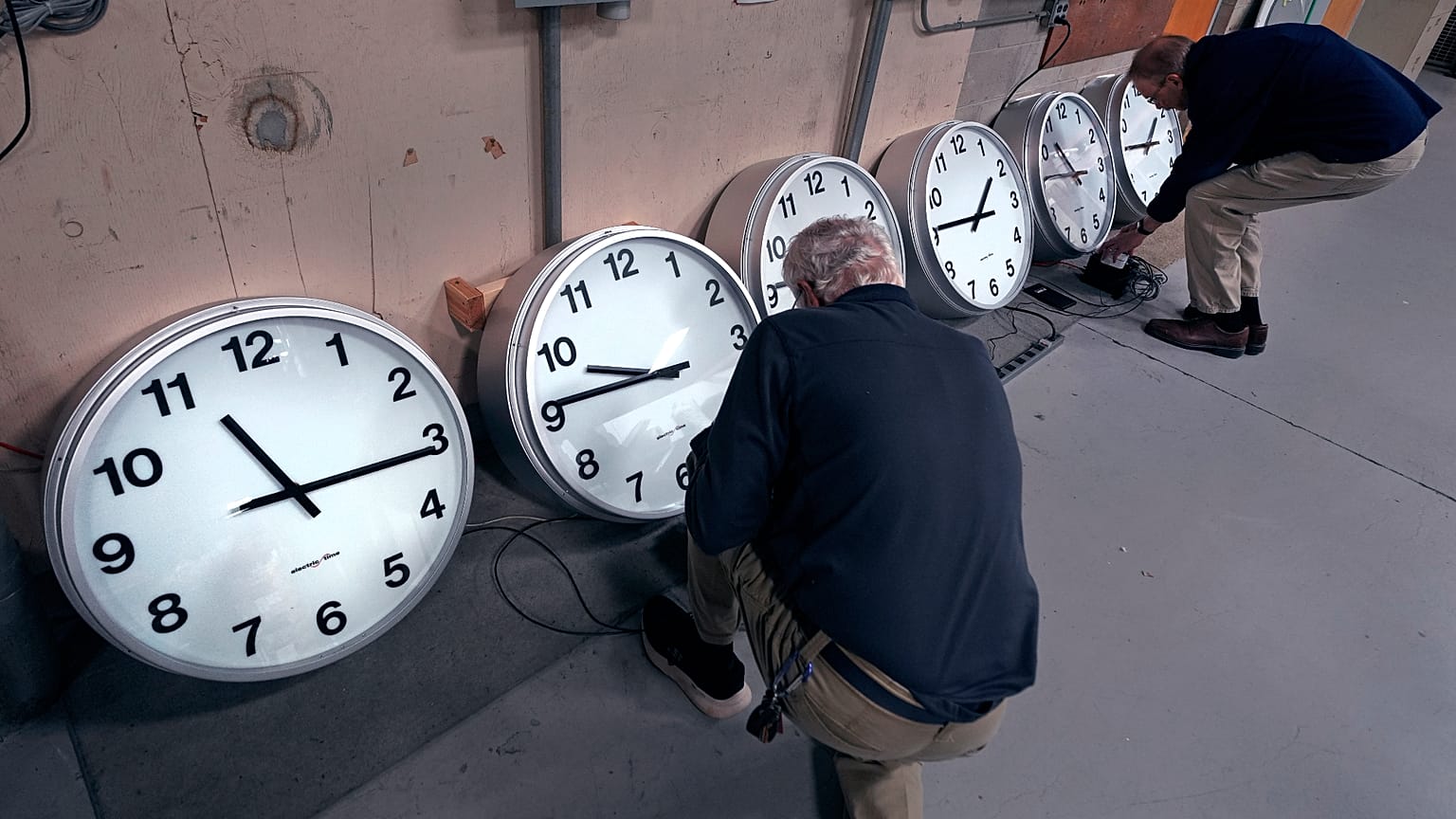 أرشيف: صانعا الساعات ريتش فين، يسار الصورة، وتوم إيرب يضبطان وحدات التحكم بالمناطق الزمنية في مجموعة من الساعات.