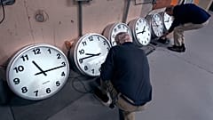 FILE: Clockmakers Rich Finn, left, and Tom Erb adjust the time zone controllers on a series of clocks.