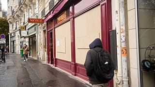 Passersby walk past a boarded-up store on the eve of a demonstration against rising living costs in Paris, Friday, Oct. 23, 2026