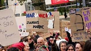 Demonstrator holds sign reading, “Marianne, never Marine,” during a protest on the sidelines of the far-right Rassemblement National congress in Orléans, France, 24 Oct 2026.
