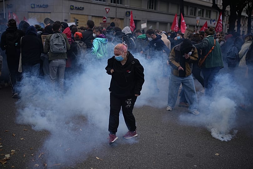 Una manifestante en medio del gas lacrimógeno durante una manifestación contra el aumento del coste de la vida en Lyon (Francia), el sábado 24 de octubre de 2026. 