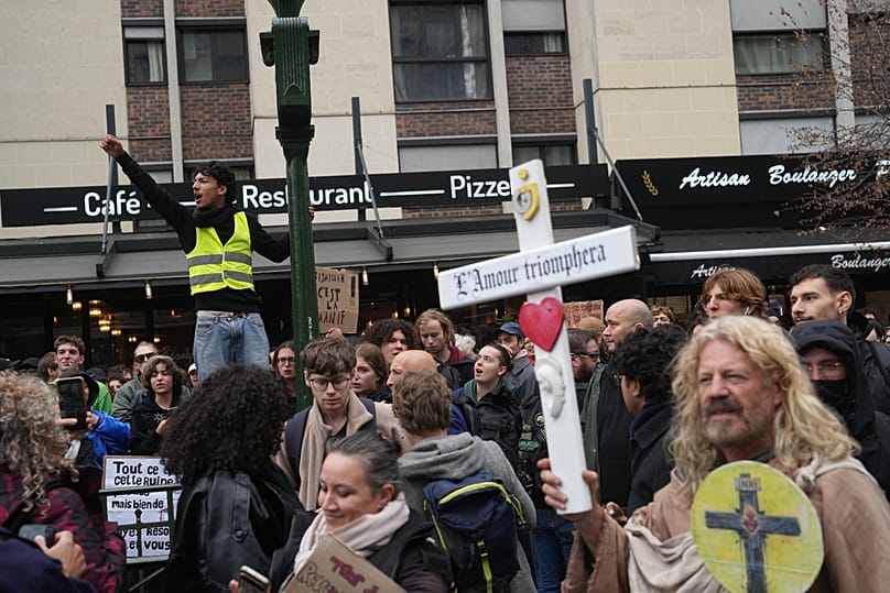 Podczas demonstracji przeciwko rosnącym kosztom życia w Paryżu, w sobotę 24 października 2026 r., jeden z protestujących trzyma krzyż z napisem „Miłość zwycięży”. 