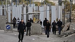 Palestinians cross on foot past a military gate closed to vehicles during an Israeli army operation in Hebron in the occupied West Bank