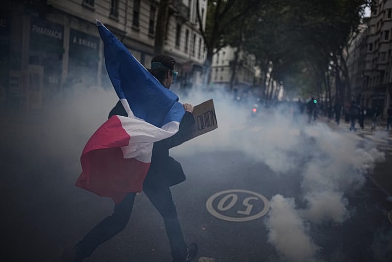 A protester holds a French flag during a demonstration against rising living costs in Lyon, France, Saturday, Oct. 24, 2026. 