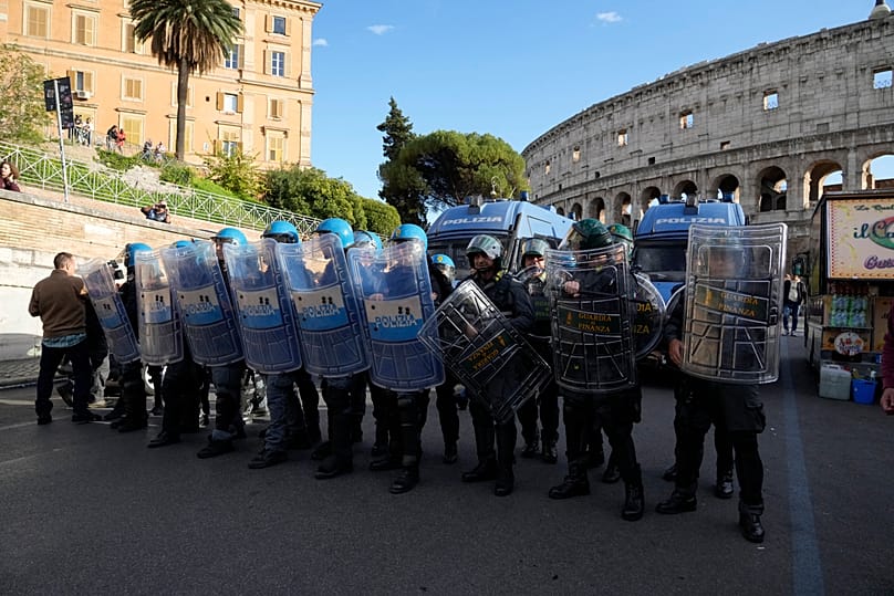 Italian anti-riot police watch antiwar activists demonstrating against rearmament and Italy's involvement in wars in Rome, Saturday, Oct. 24, 2026, 