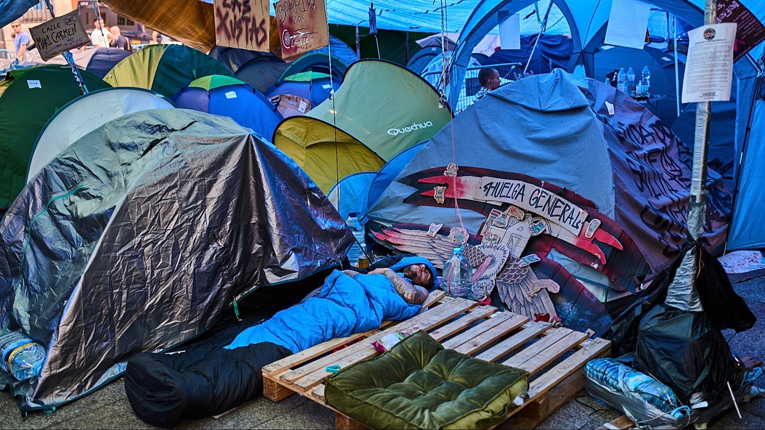 ARCHIVO: Un hombre duerme en un campamento improvisado en la Puerta del Sol en Madrid, España, el sábado 17 de octubre de 2026.