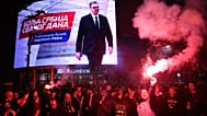 People celebrate after Aleksandar Vučić, leader of the Serbian Progressive Party, seen on top display, conceded defeat in the parliamentary election in Belgrade, 25 Oct 2026