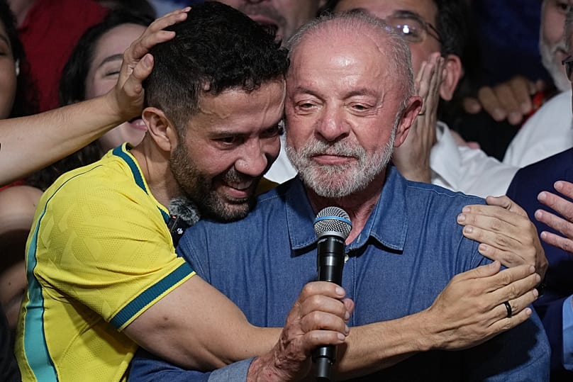 Brazilian lawmaker Andre Janones embraces Lula as he delivers a victory speech after winning a fourth term in the presidential runoff in Brazil, Sunday, Oct. 25, 2026.