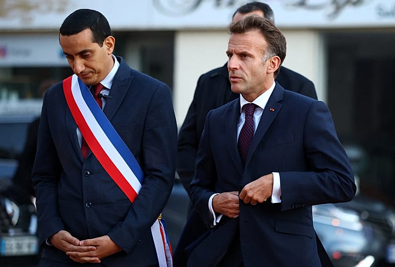 French President Emmanuel Macron walks with Mayor of Trappes Ali Rabeh, left, as he arrives for a meeting at the town hall in Trappes, near Paris, France, Friday Oct. 23, 2026