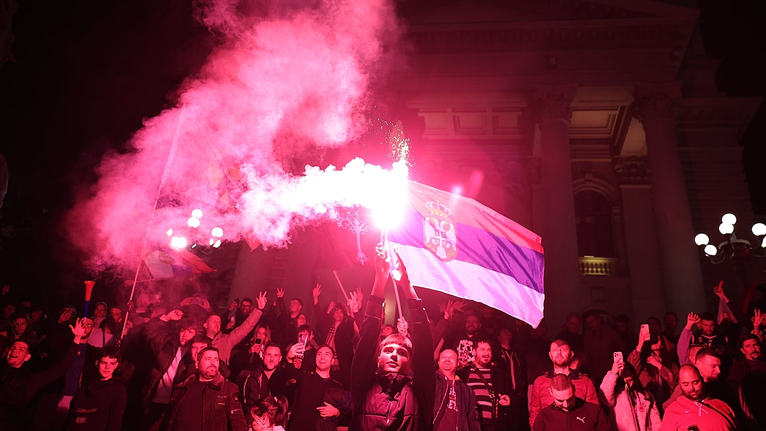 People celebrate outside the National Assembly, after Aleksandar Vucic, leader of the right-wing Serbian Progressive Party (SNS) conceded defeat in the parliamentary election.