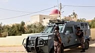 عناصر من الشرطة الأردنية يقفون بجانب مركبة مدرعة خارج كنيسة القديس جاورجيوس للروم الأرثوذكس