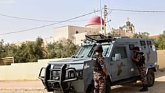 عناصر من الشرطة الأردنية يقفون بجانب مركبة مدرعة خارج كنيسة القديس جاورجيوس للروم الأرثوذكس