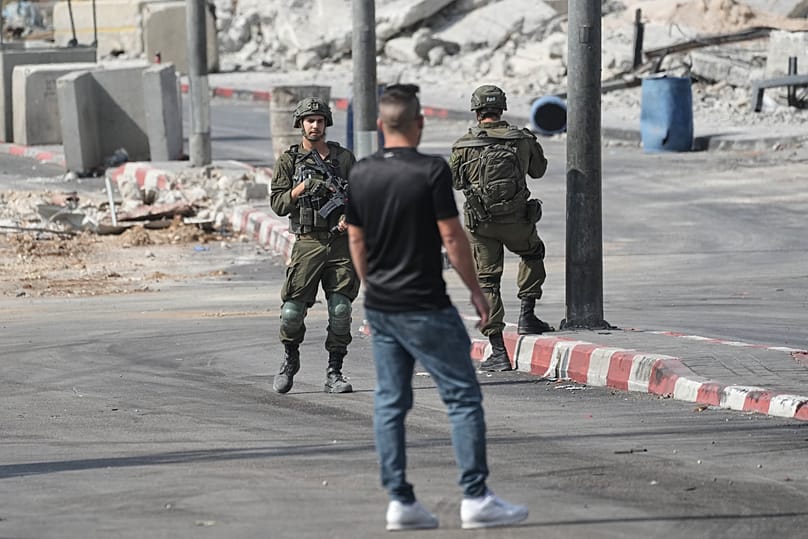 فلسطيني يقف بجانب جنود إسرائيليين خلال عملية عسكرية في الخليل بالضفة الغربية المحتلة، 24 تشرين الأول/أكتوبر 2026. 