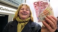 Hildegard Stein laughs as she waves euro bills she got from an ATM in a bank in Frankfurt, Germany, shortly after midnight Tuyesday Jan. 1, 2002. 