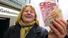Hildegard Stein ri enquanto exibe notas de euro levantadas numa caixa multibanco em Frankfurt, Alemanha, pouco depois da meia-noite de terça-feira, 1 de janeiro de 2002.